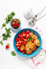 Pancake cereal, mini pancakes with fresh strawberry in a bowl with maple syrup