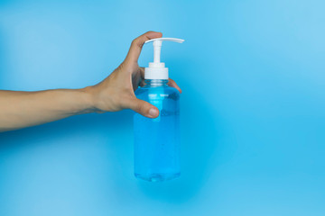 Hand holding alcohol gel. Hand holding alcohol gel sanitizer. Women hand holding alcohol gel sanitizer in pump head bottle on light blue background . With copy space.