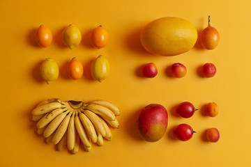 Set of delicious tropical fruits for consumption. Lemons, cumquat, peaches, tamarillo, bananas, melon on yellow background. Nutritious crops rich in vitamins used as ingredients for fruit salad