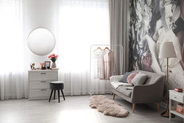 Stylish room interior with dressing table, mirror, sofa and floral wallpaper