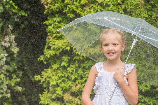Littel girl with umbrella playing in the rain.
