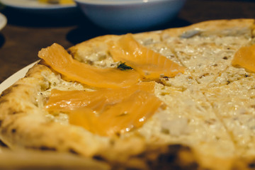 view of slice piece Salmon Sashimi pizza. Hand holding slice of pizza.