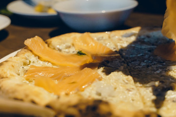 view of slice piece Salmon Sashimi pizza. Hand holding slice of pizza.