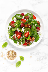 Fresh spinach salad with strawberry, pine and pecan nuts, goat cheese, maple syrup dressing