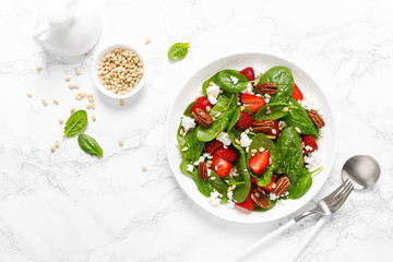 Fresh spinach salad with strawberry, pine and pecan nuts, goat cheese, maple syrup dressing