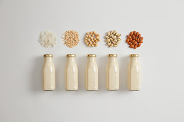 Fototapeta na wymiar Vegetable white milk made of cocnut, oat, hazelnut, pistachio and almond. Ingredients for preparing vegetarian beverage. Product contains good amount of protein, vitamin D, calcium. Healthy drink