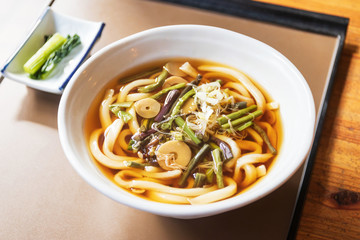 Japanese udon noodles with soup in a bowl on table with sunlight through the window.