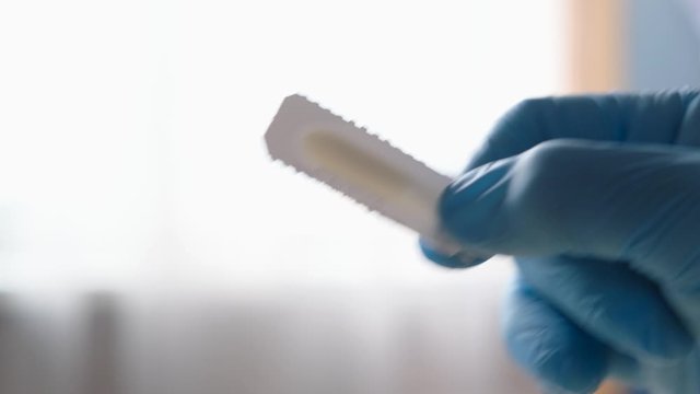 Doctor's gloved hand showing preparation for suppository for hemorrhoids