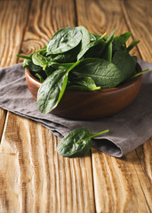 Baby spinach  in wooden bowl on table, green healthy ingredient