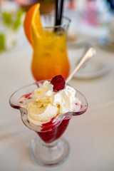 słodki deser z bitą śmietaną i maliną