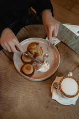 girl having breakfast with cheesecakes with boiled condensed milk next to it is a glass of milk coffee