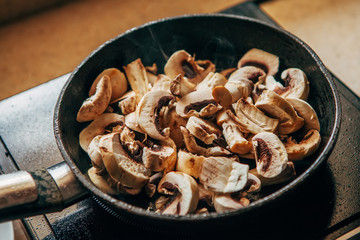 Champignons are fried in a pan. Cooking at home.