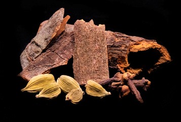 Close up image of cardamom clove and cinnamon with black background.