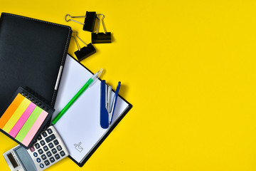 Office supplies on a yellow background. Diary, pens, pencils, calculator, notepad. Back to work. The concept of business, work. Place for text.
