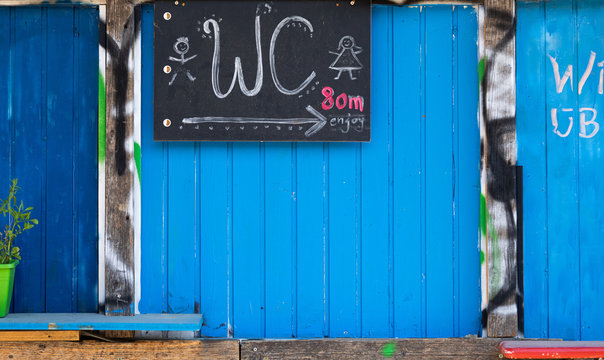 water toilet sign on a chalkboard whitch is fixed on a blue weathered wooden wall