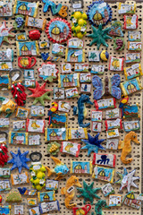 Close up on many handcrafted ceramic refrigerator magnets in beautiful vivid colors and designs with price label at a store in Vietri/Italy selling traditional souvenirs