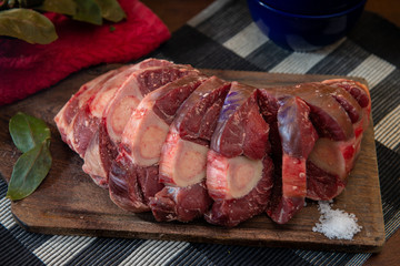 Osobuco carne cruda e ingredientes sobre tabla de madera 