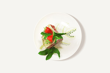 Slice of homemade cake with strawberries on a plate on a white background from above close-up