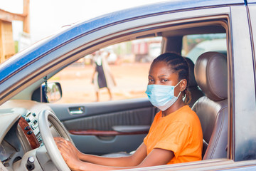 young beautiful african lady in a vehicle wearing face mask to prevent, preventing, prevented herself from the outbreak in the society