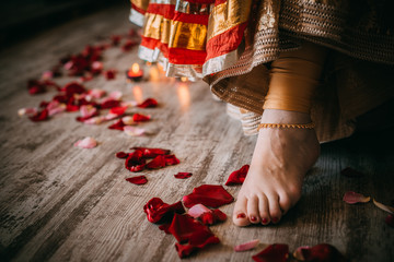 woman legs with rose petals on wooden background