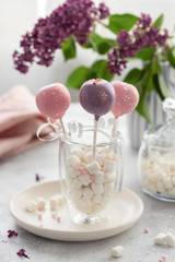three delicious cake pops in a double wall glass with marshmallows on a background flowers. holiday dessert. vertical image.