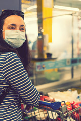 Asian young woman wearing a hygiene protective mask over her face while walking at the crowded shopping mall. Covid19 influenza in crowded place. woman wearing a mask in the supermarket. toned