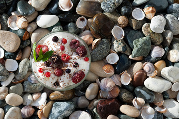Bowl of ice cream with berries on the beach, top view with copy space