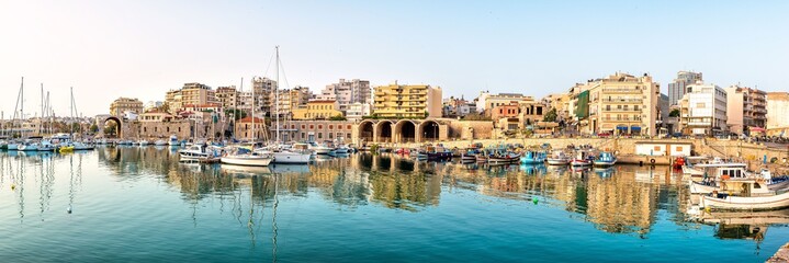 Fototapeta na wymiar Panoramic photo of Heraklion in the early morning during sun rise, view to the old part of the town/city with its antient buildings and yaught port 