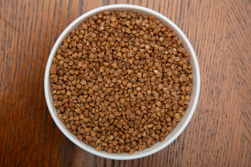 Buckwheat in a white Cup on a brown table.