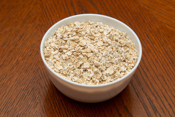 Oatmeal in a white Cup on a brown table.
