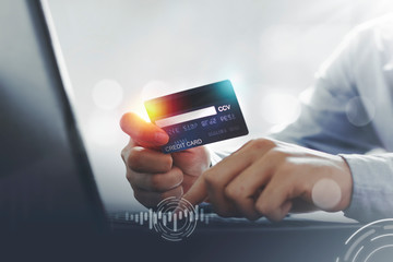 Asian man showing credit card for laptop payment for online shopping at home with copy space. E-payment technology, electronic transactions or mobile phone financial application concept