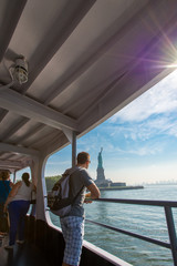 Jeune homme regardant la statue de la liberté sur le pont d'un bateau