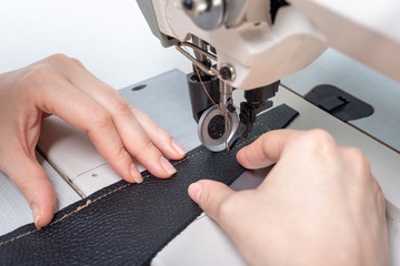 girl sews on a sewing machine scribbles fabric and leather making a product