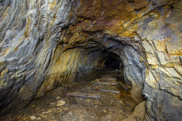 Underground abandoned mica ore mine tunnel with yellow dirt