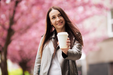 Close-up portrait of a brunette girl on a background of Japanese cherry blossom tree.