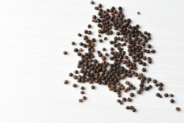 Black peppercorns in bowls on white wooden background