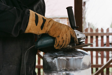 A man in a home workshop is engaged in reworking a metal product outdoor. Circular Economy concept. People lifestyle.