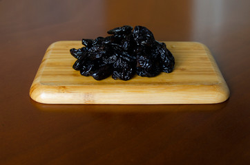 prunes dried black plum lies on a wooden board