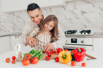 Father's day. Dad and his child daughter are cooking and having fun together in the kitchen. Family holiday.