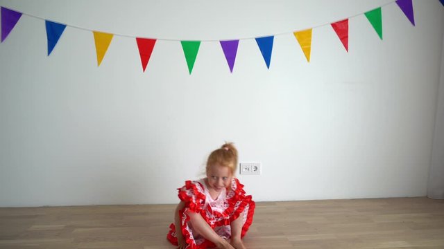 Funny redhead girl dancing turning around and fall down. Child in dress