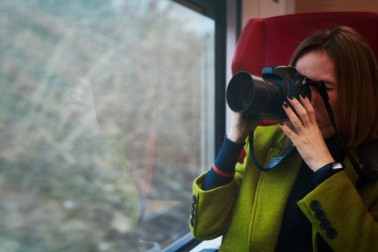 Woman tourist takes pictures of landscapes in a train window.