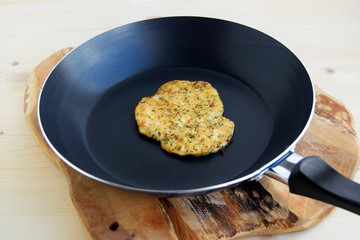 Chicken fillet fried in a pan. Chop is prepared with herbs and spices. Fresh hot roasted meat. Closeup black and wooden background.