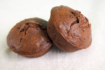 two gluten-free chocolate muffins on a light background cooked at home