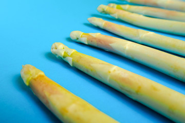 raw pods of white asparagus lie on a blue background . vitamin-rich vegetables that are good for your health