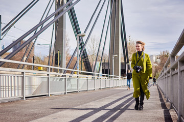 Woman tourist with a camera is walking on the bridge. Wind blowing hair. Travel, new city.