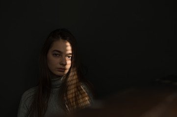 portrait of a girl against a dark background, the light from the window falls on the girl’s face, I create shadow stripes on the blinds