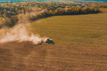 Side view of an aircraft flying over a field cultivated by a crawler tractor during a crisis in the...