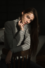 a girl in a turtleneck, with long hair, sits by the window, a girl of model appearance