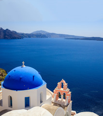 White church with blue dome against blue sea and sky background. Oia Santorini, Greece.