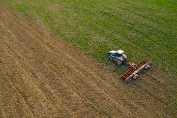 Side view of an aircraft flying over a field cultivated by a crawler tractor during a crisis in the...